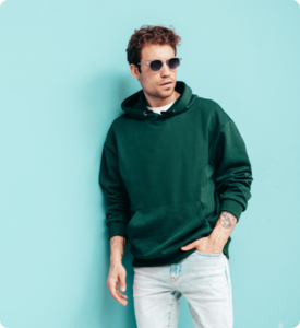 handsome-confident-hipster-modelsexy-unshaven-man-dressed-summer-stylish-green-hoodie-jeans-clothes-fashion-male-with-curly-hairstyle-posing-studio-isolated-blue